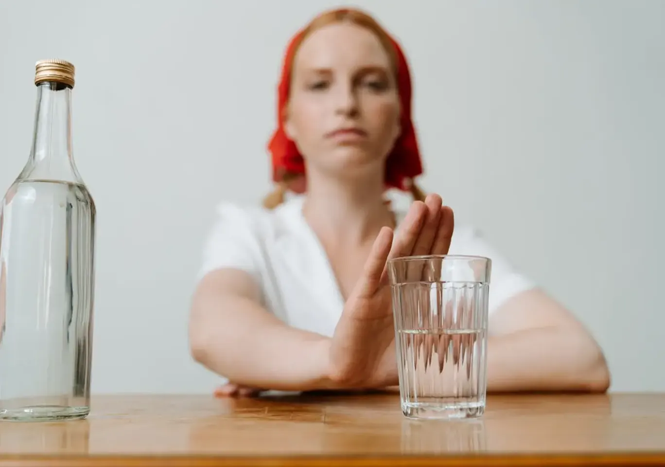 Leczenie alkoholizmu Tarnów: kobieta odsuwa butelkę i sięga po wodę